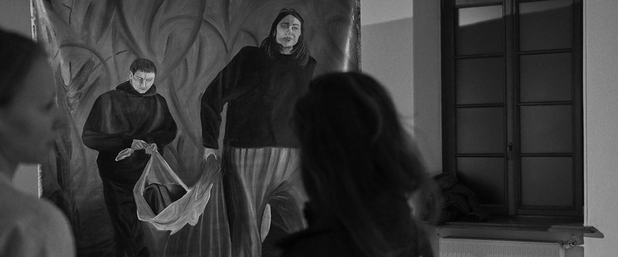 Zdjęcie czarno-białe. Dwie kobiety oglądają zawieszone pod sufitem płótno-obraz na wystawie w sali galerii SDK.