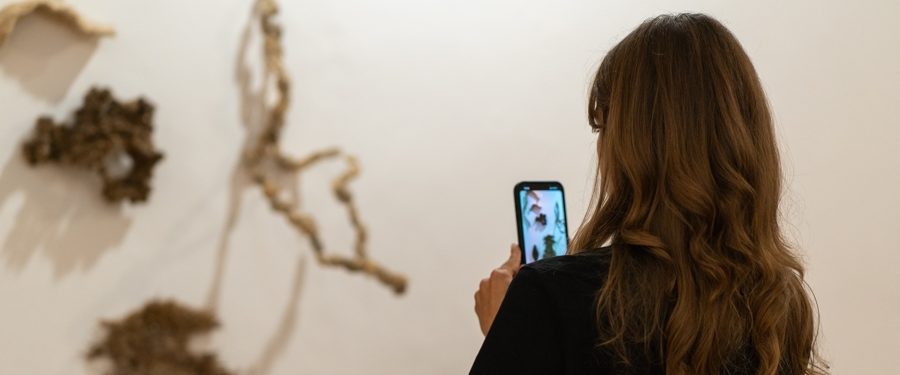 kobieta fotografuje telefonem element wystawy plastycznej
